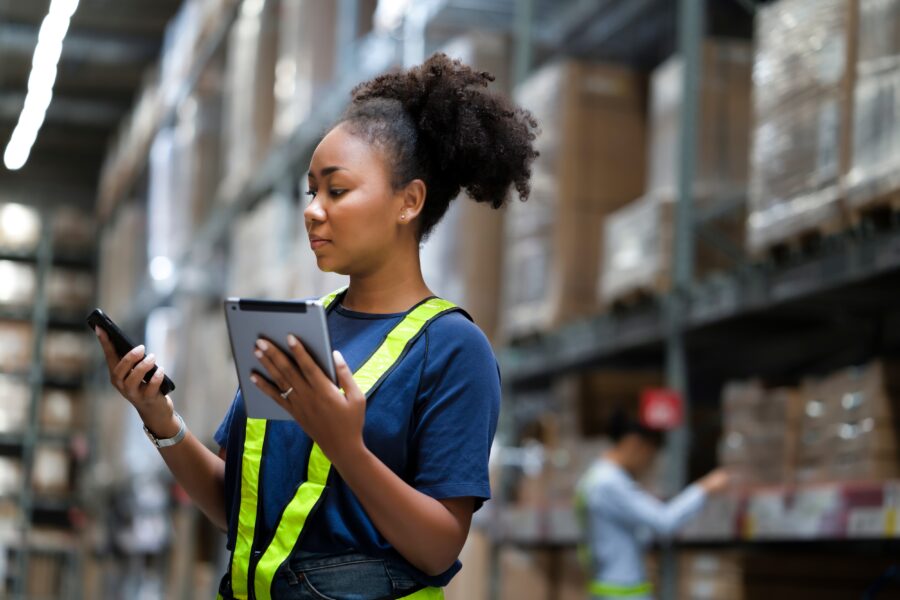 Young woman in a warehouse using tablets and scanners to manage inventory